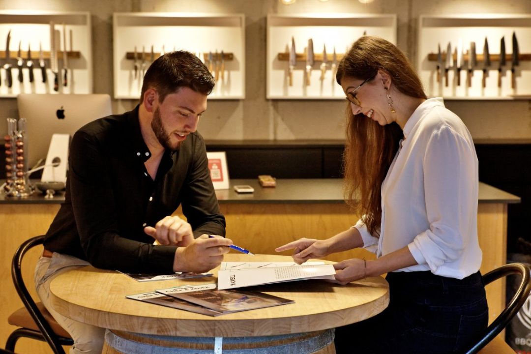 Brecht en Alissa aan tafel kijkend in brochure in de garage, start van Chef & Knife