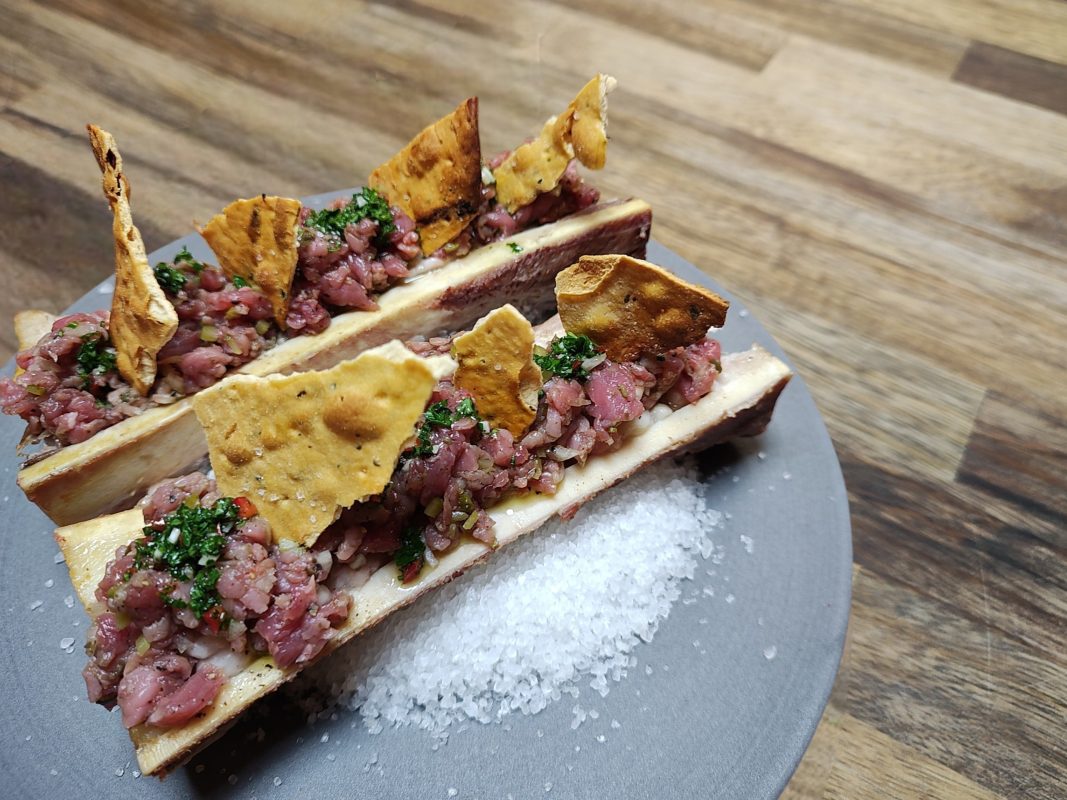 Gerookte mergpijp van de kamado met steak tartaar, chimichurri en krokante toast.